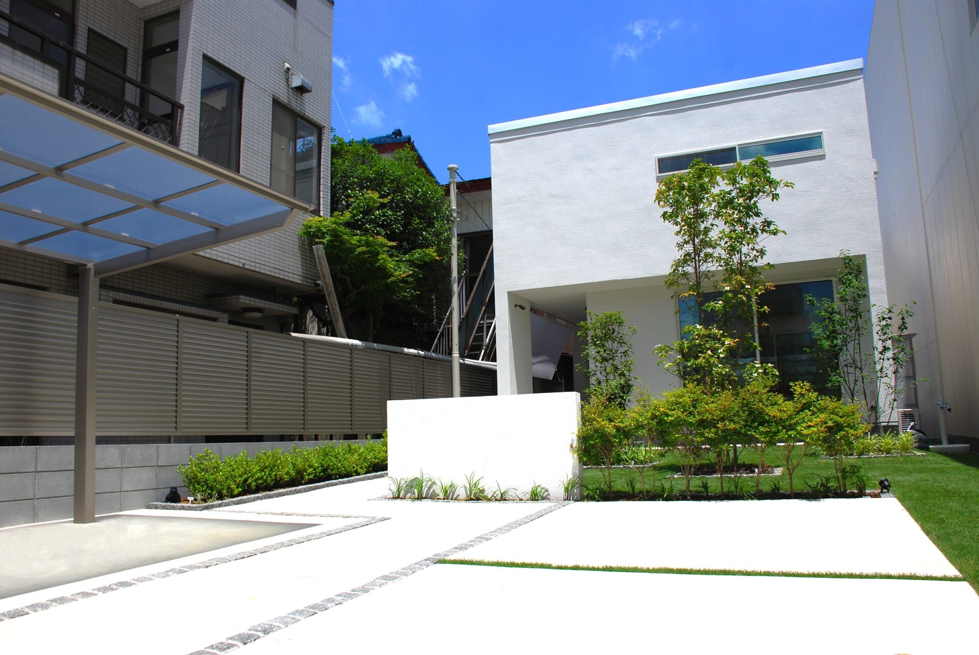 加須市の真白い壁と直線デザイン、植栽が美しい家を引き立てるシンプルを極めたオープン外構の門柱・アプローチ